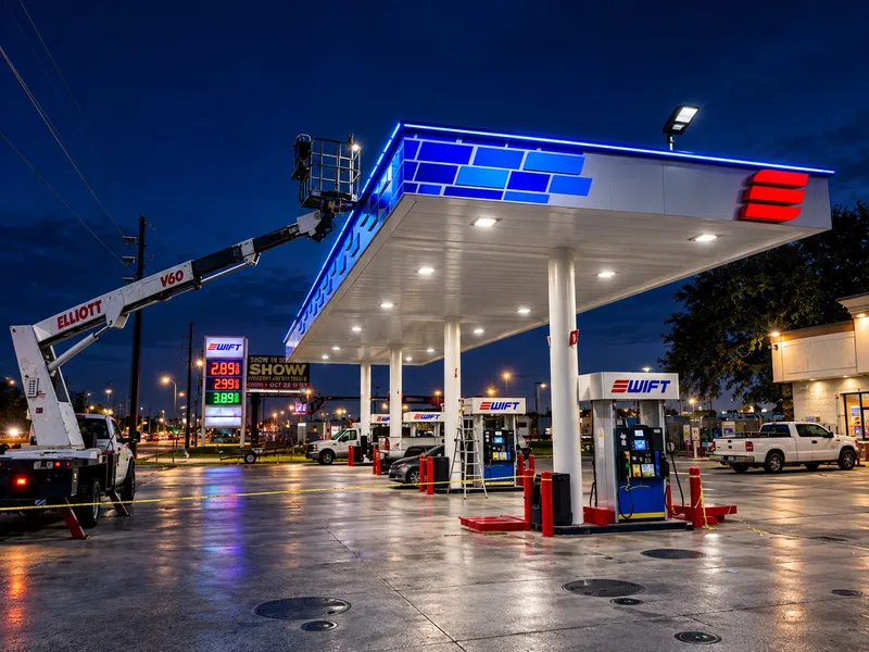 Swift fuel station at dusk during the brand conversion: a bucket truck raised to the canopy edge, new blue and white fascia with the red Swift logo, rebranded dispensers on lit islands, and the price pylon by the road